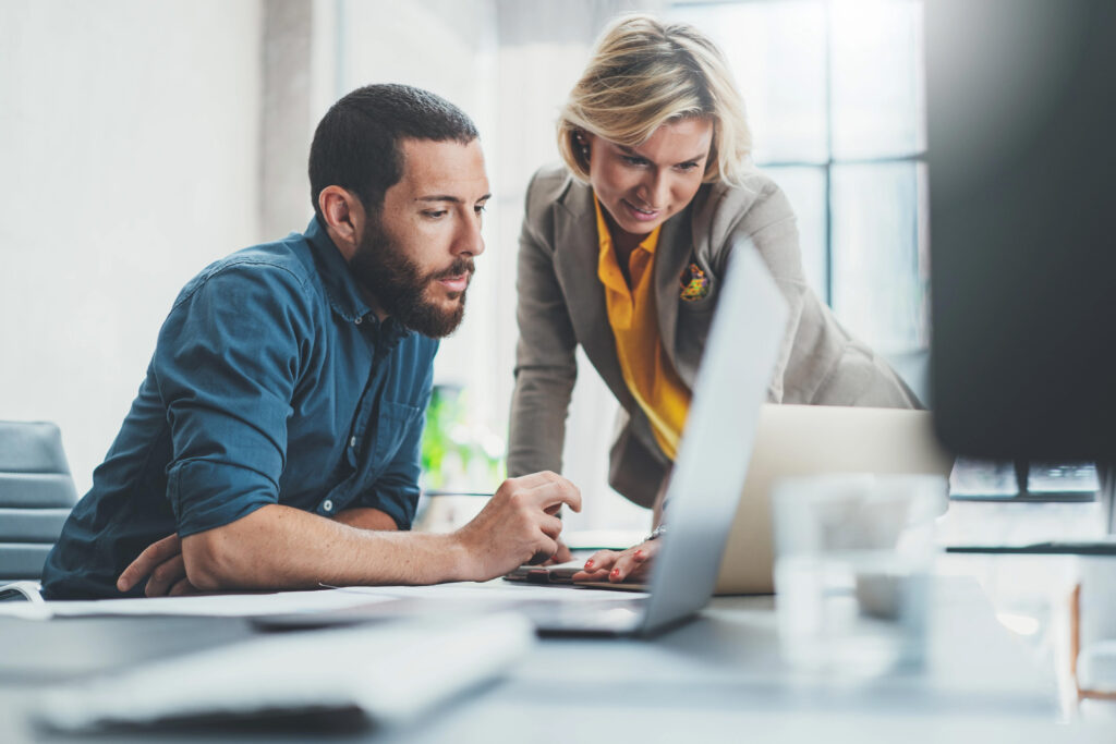 Man and woman dressed in business casual looking at a laptop