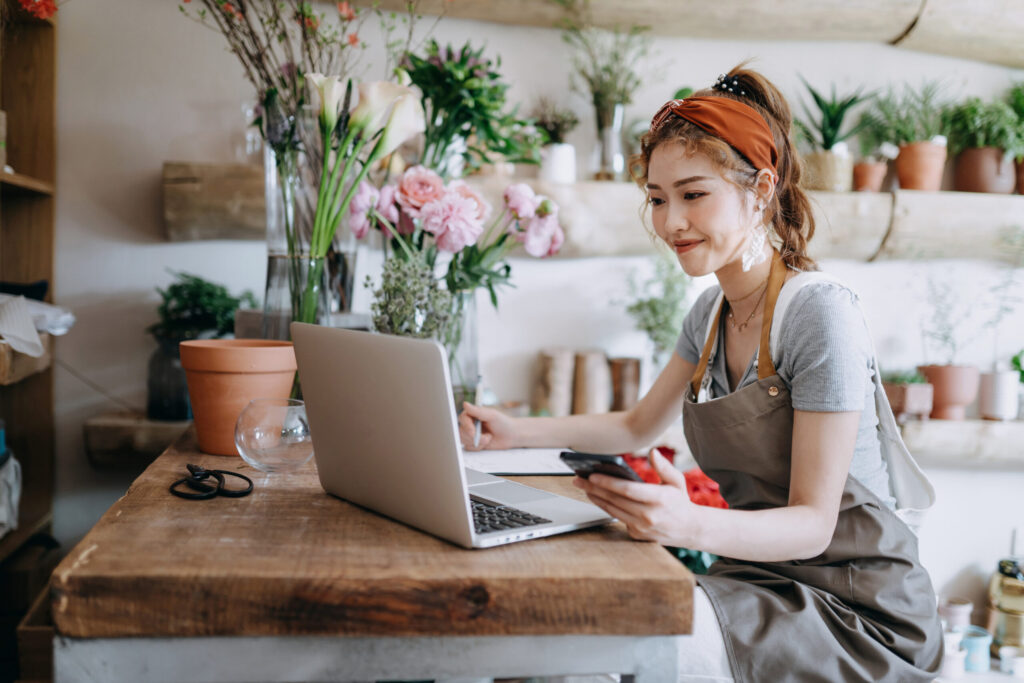 Floral business owner with an apron on using her laptop