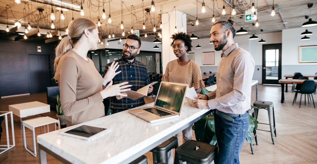 A group of people stands around a table in a modern office space